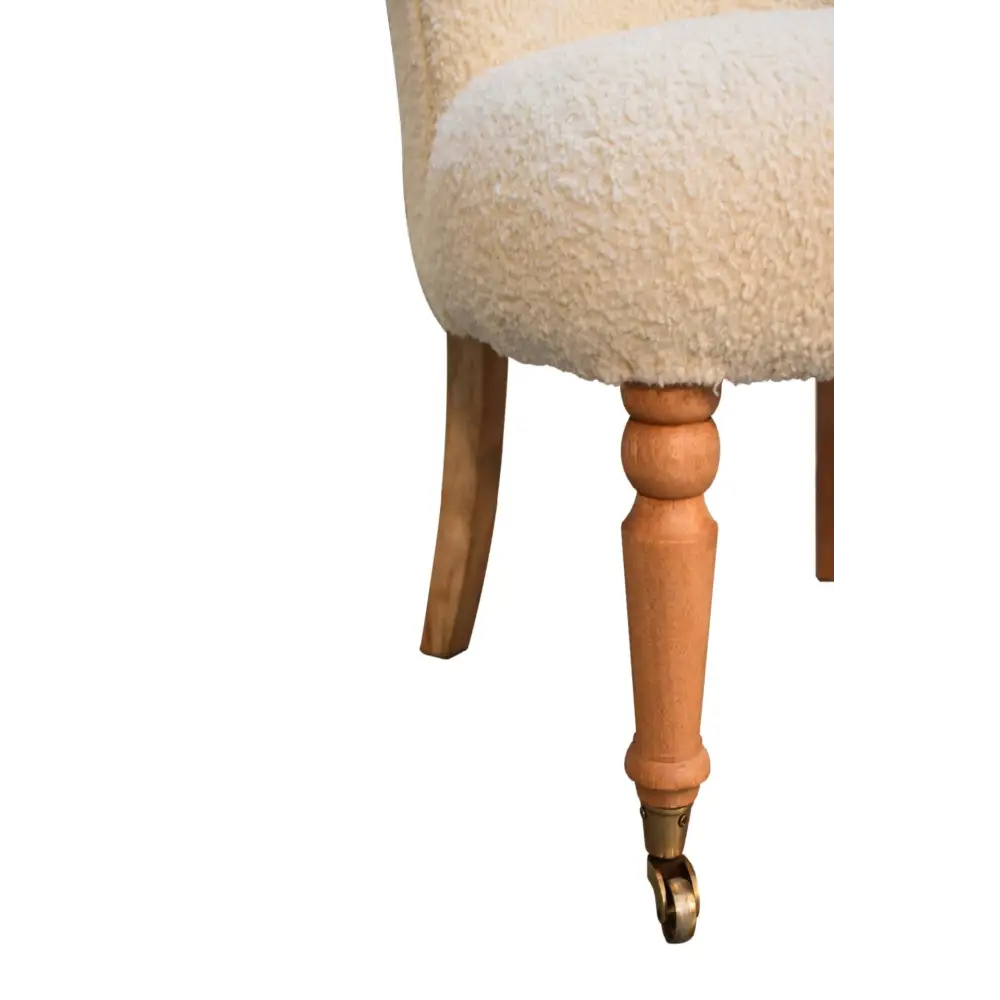 Close-up of a chair with wooden legs and a fluffy boucle cushion