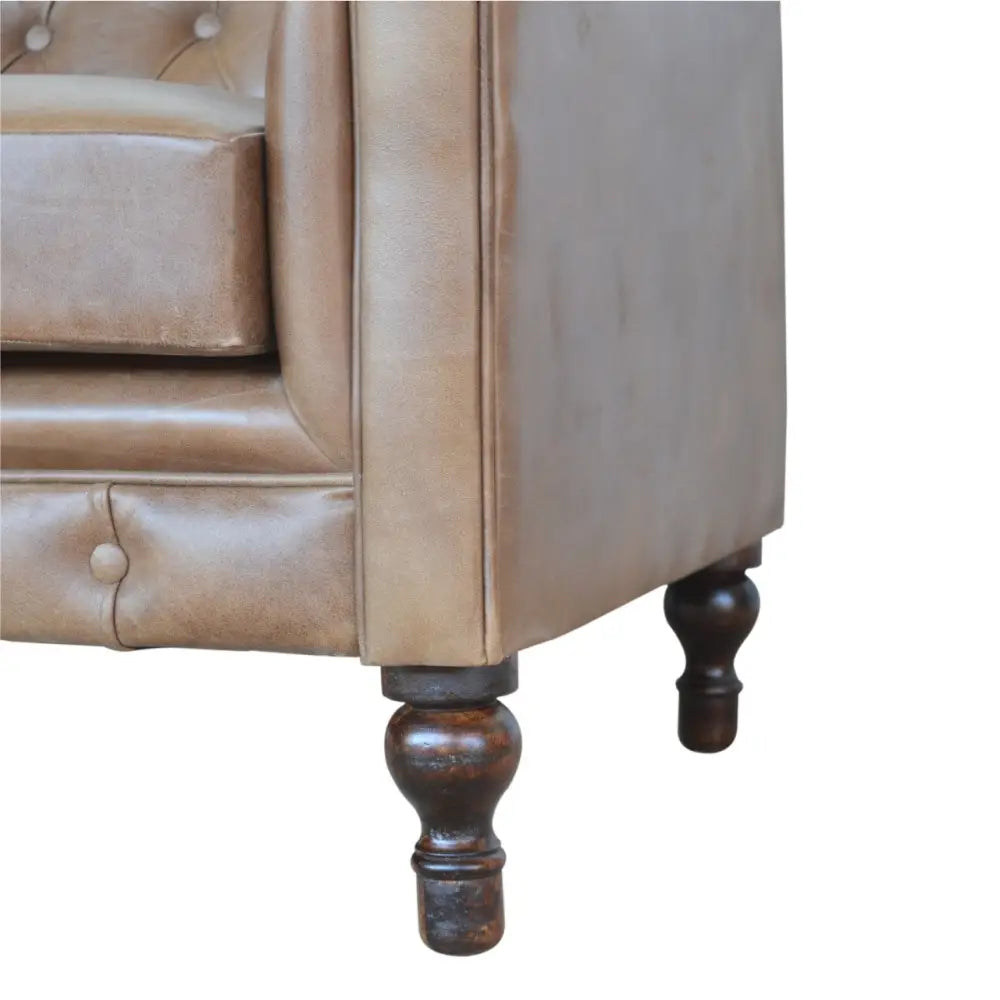 Buffalo leather chesterfield sofa. Close-up of a brown leather sofa with wooden legs 